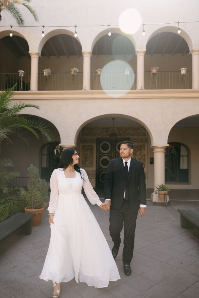 Man and woman holding hands and walking through a courtyard