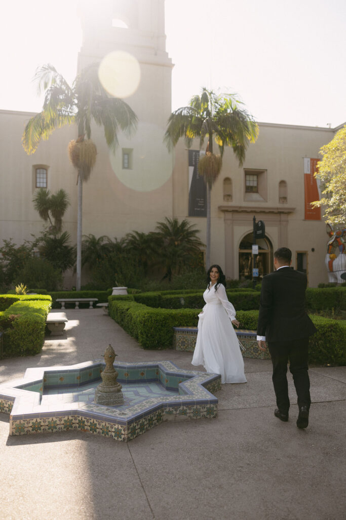 Couple strolling through Alcázar Garden for their Balboa Park engagement photos in California