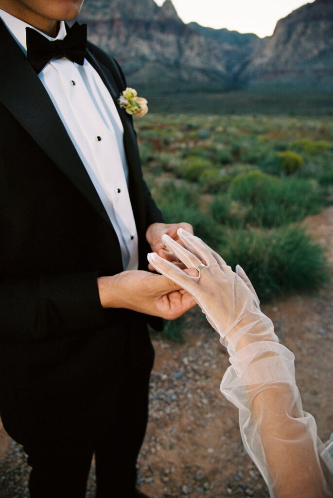 Film photo of a groom putting a bride gloves on - digital vs film wedding photography