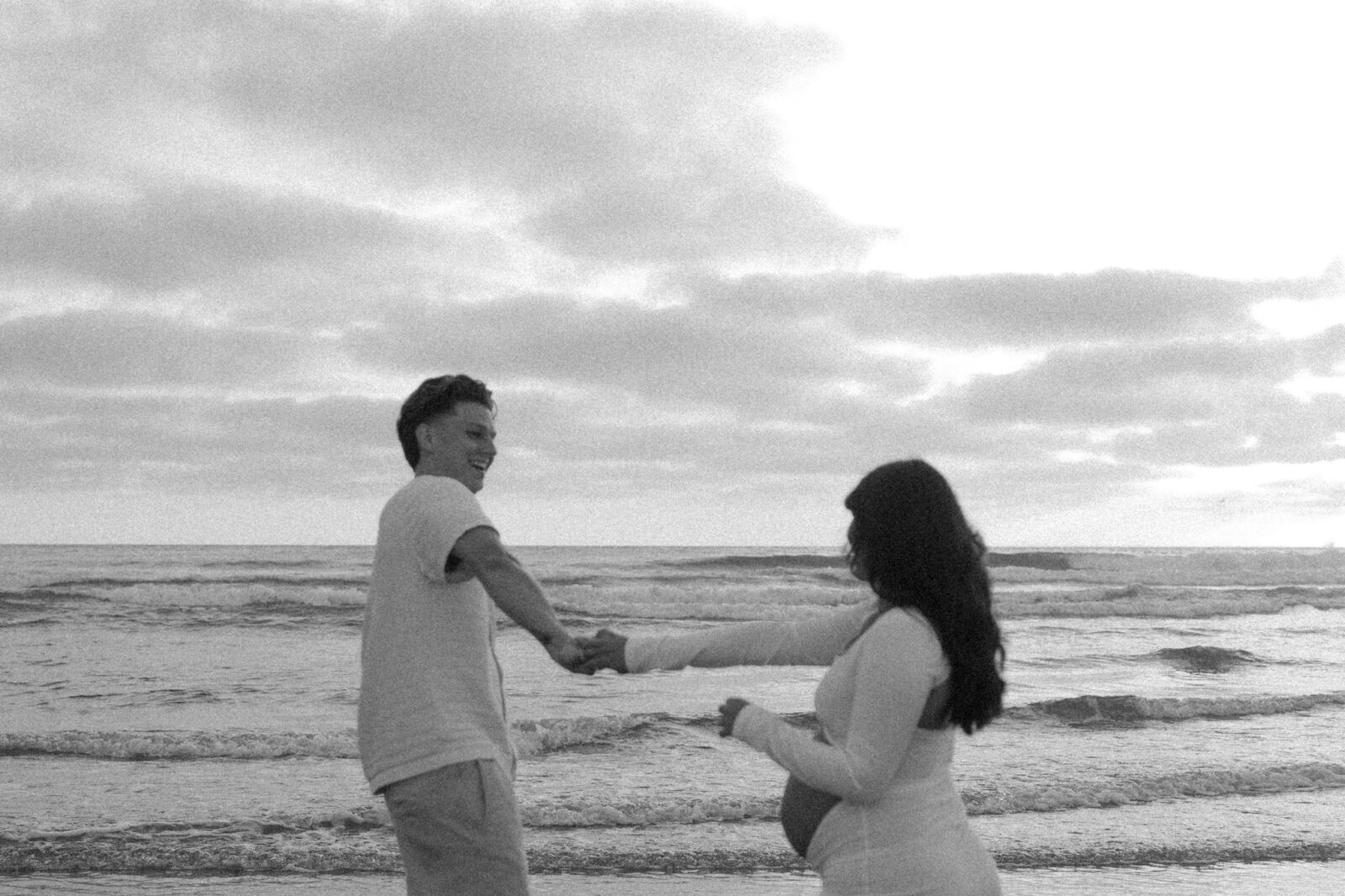 Black and white photo of a man and woman dancing on the beach