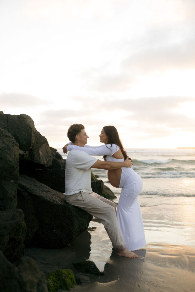 Man and woman leaning against beach rocks