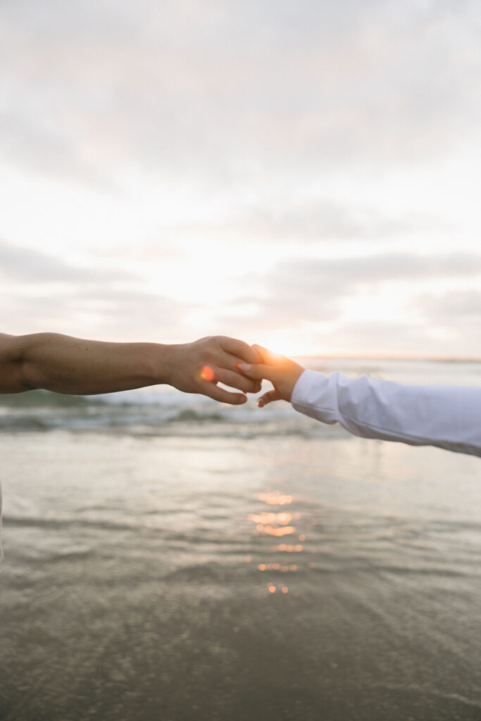 Man and woman holding hands at sunset on the beach