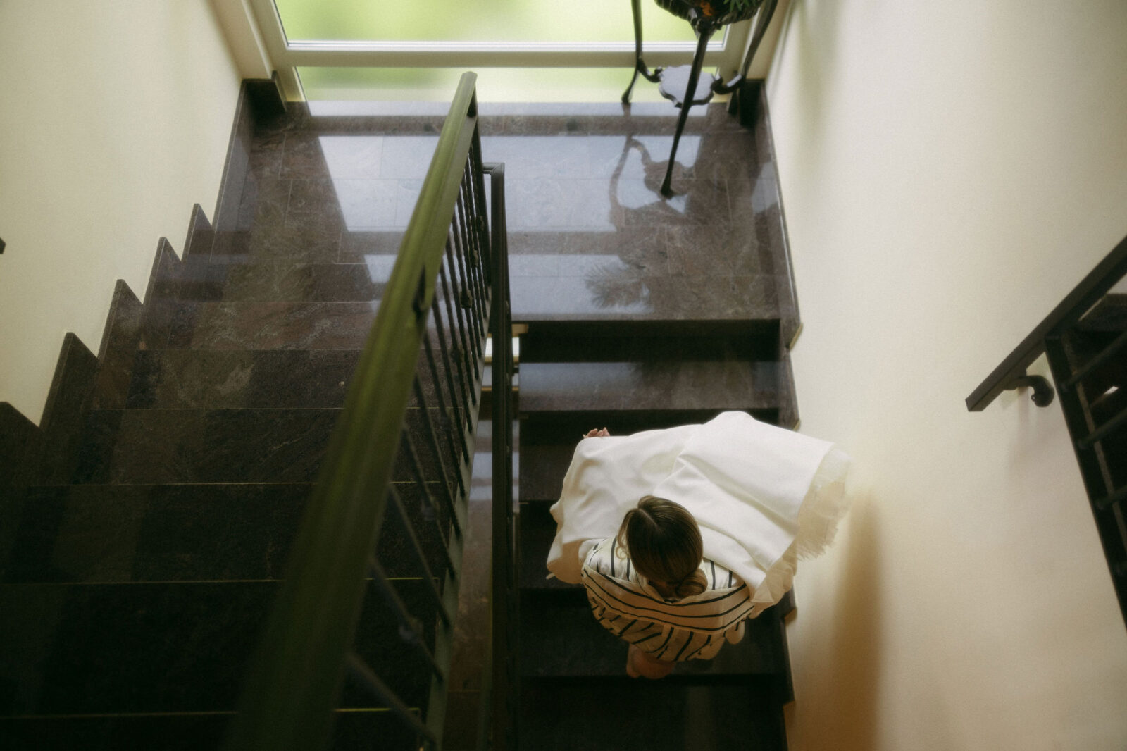 Bride walking up a staircase while carrying her wedding dress