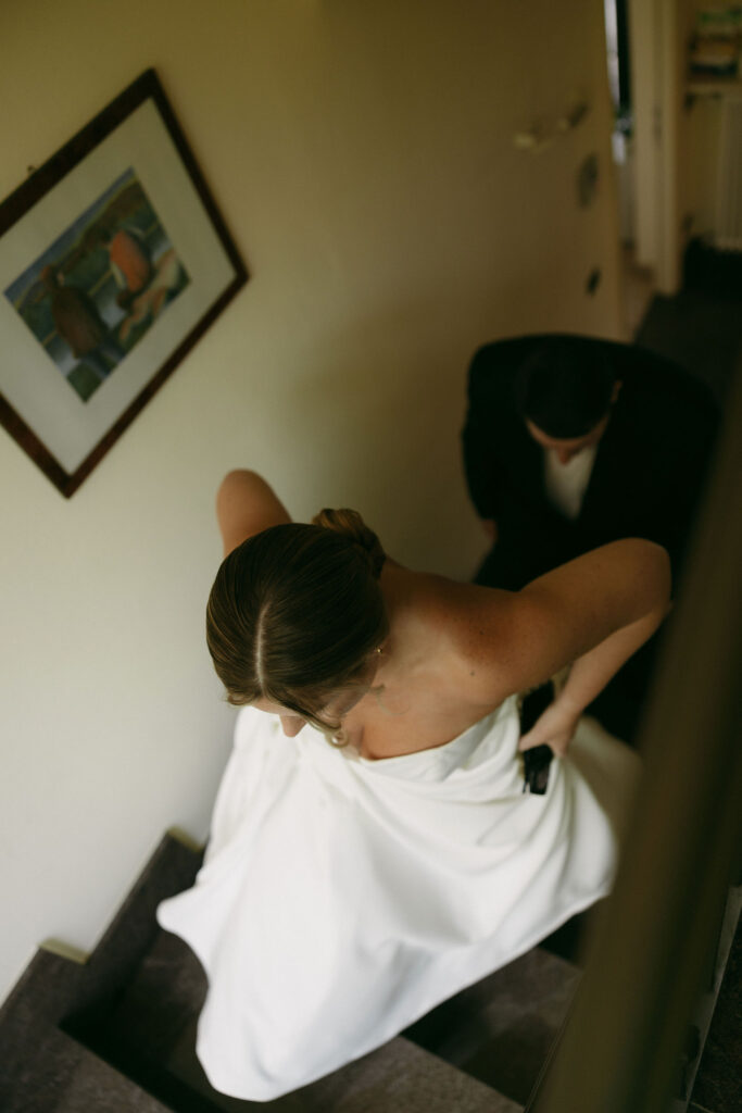 Documentary wedding photo of a bride and groom walking up the stairs of their Airbnb 