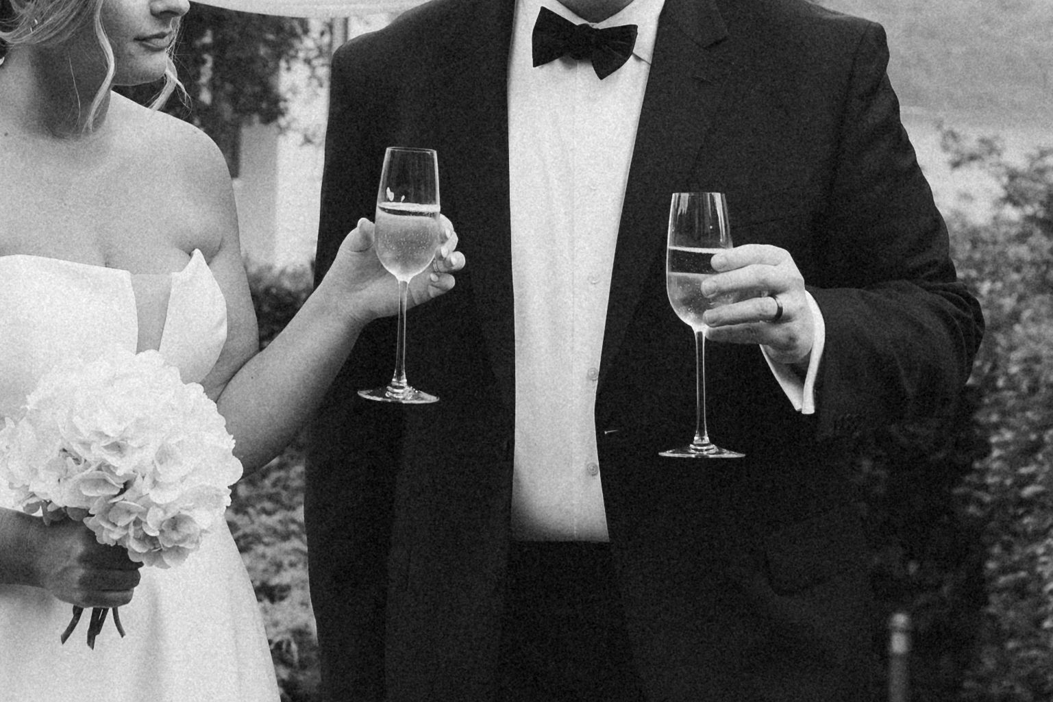 Black and white photo of a bride and groom with champagne after their ceremony