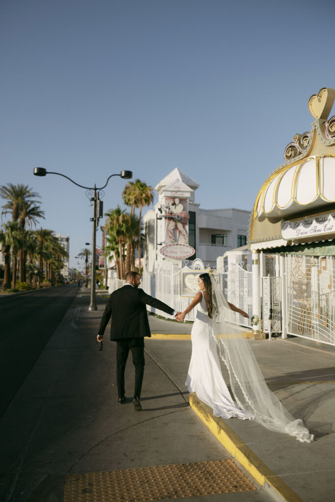 Bride and groom walking down the street holding hands