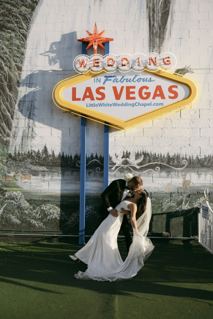 Bride and groom kissing underneath a Las Vegas sign