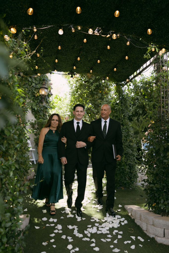 Groom being walked down the aisle by his parents