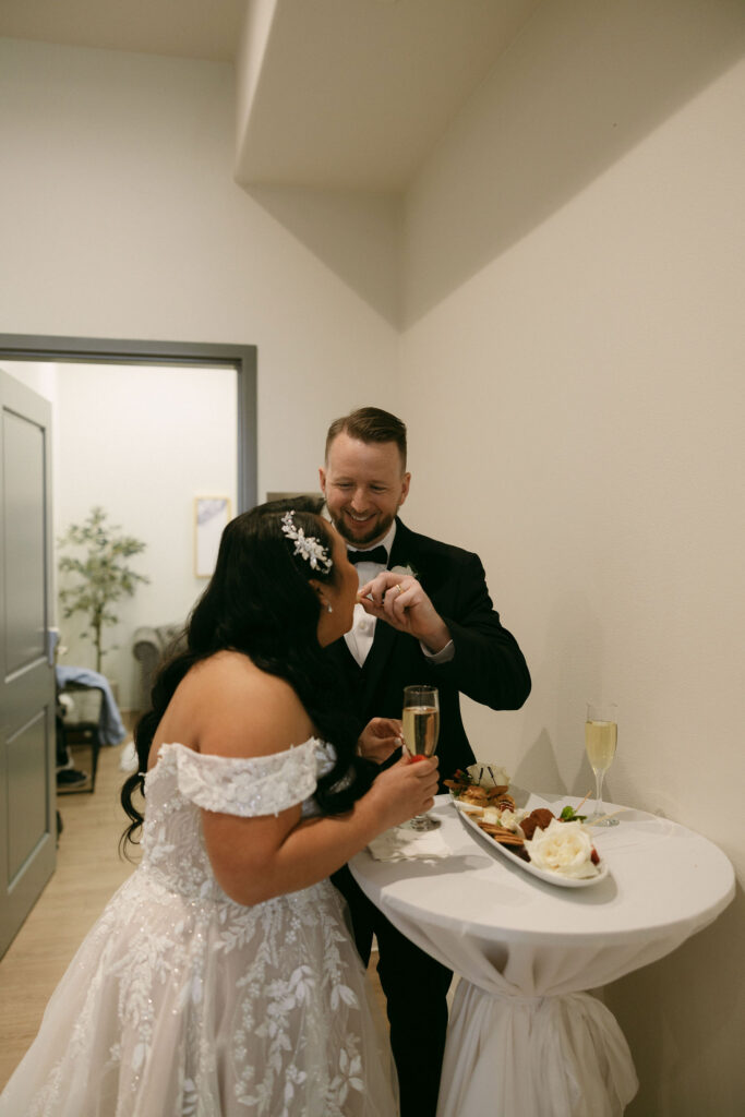 Groom feeding his bride from their personal charcuterie board