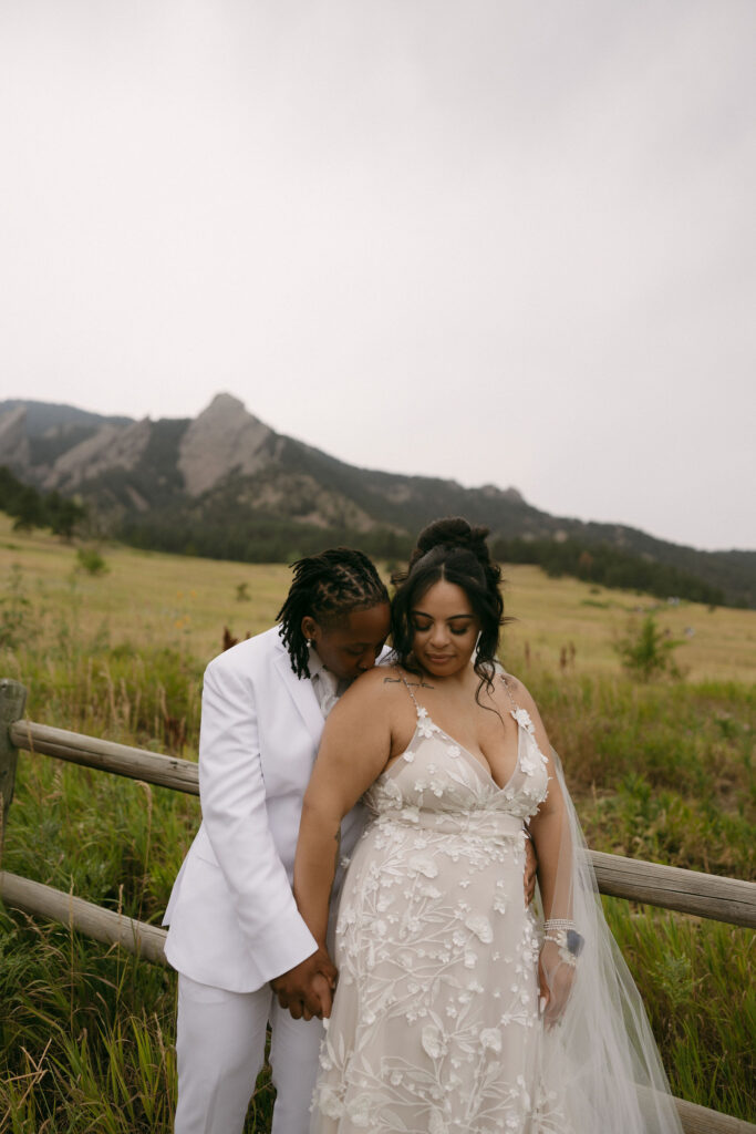 Couple posing along a rustic fence for their Chautauqua Park wedding portraits in the mountains