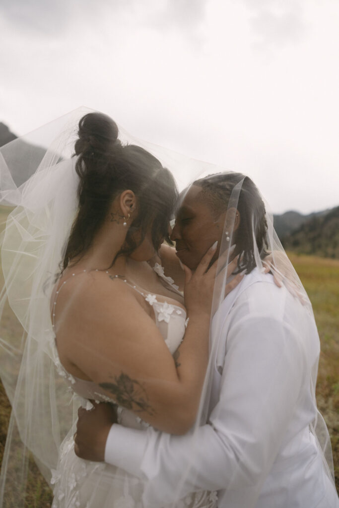 Couple posing under a wedding veil for their Chautauqua Park wedding portraits