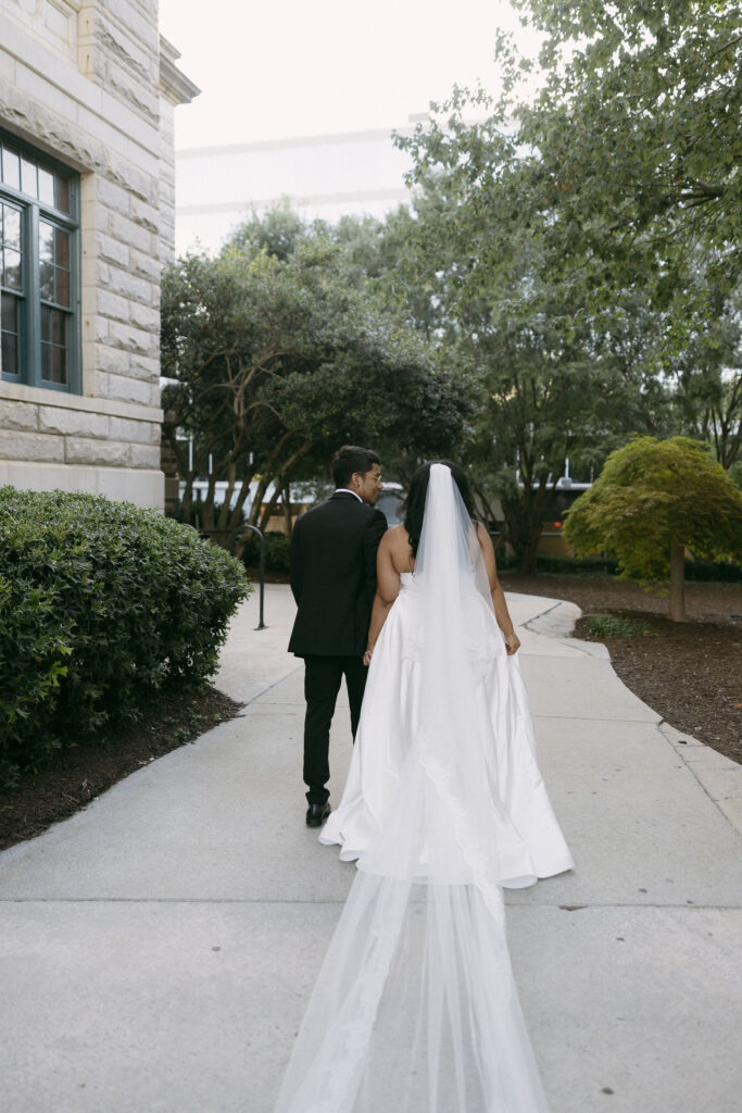 Bride and groom walking down a sidewalk holding hands