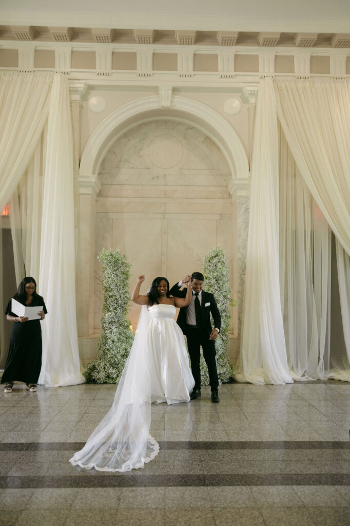 Bride and groom celebrating with their arms in the air after their intimate Historic DeKalb Courthouse wedding ceremony in Atlanta, Georgia