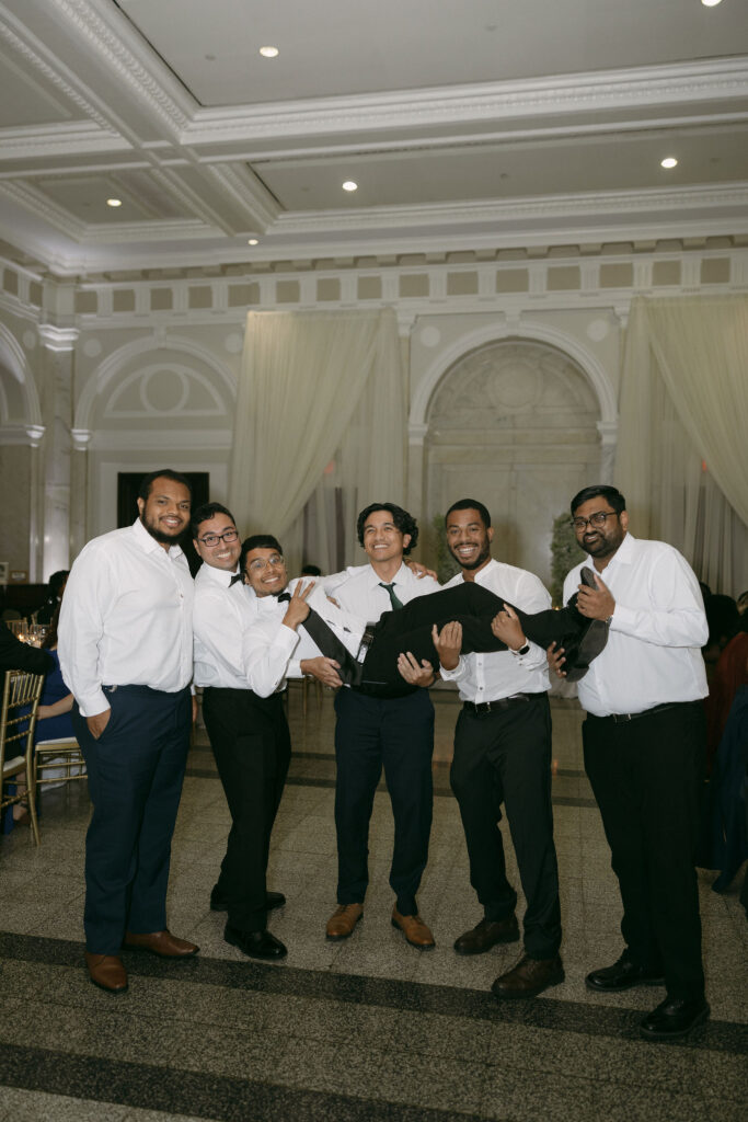 Groom being lifted up by friends during his reception