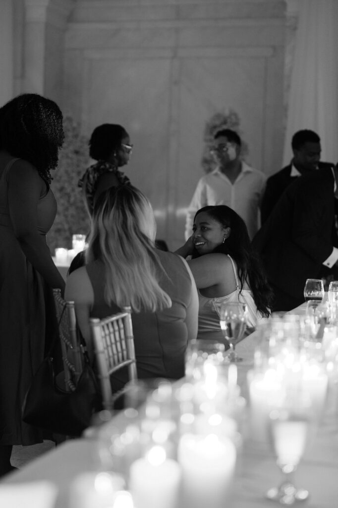 Black and white documentary wedding reception photo of a bride mingling with guests