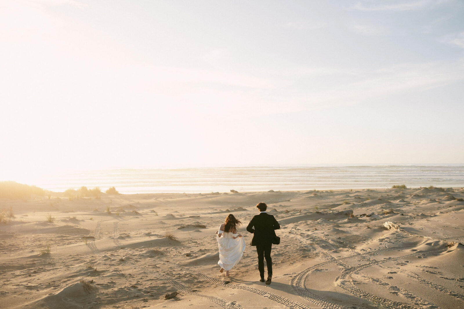 Couple running along the beach during their Northern Coast elopement at Nehalem Bay