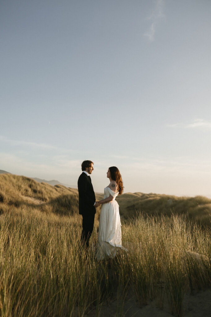 Couple posing in the beach grass during their Northern Oregon Coast elopement at Nehalem Bay State Park