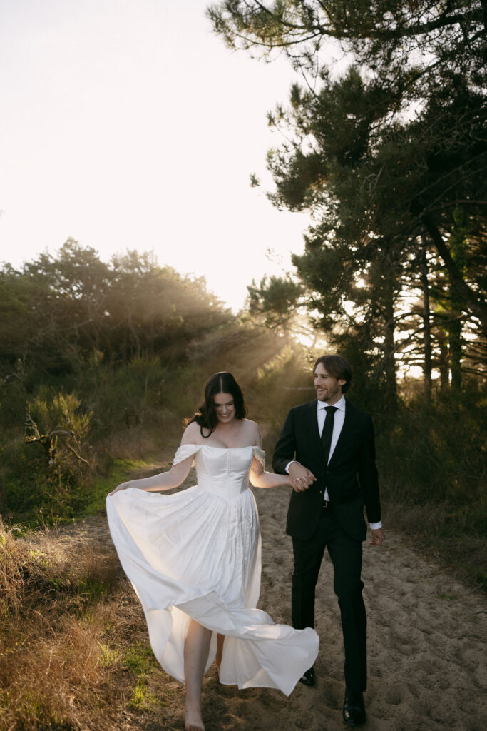 Couple walking down a sandy hill during their intimate elopement