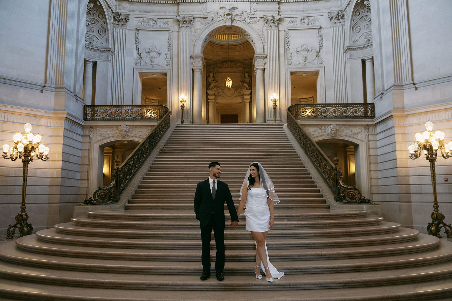 Couple posing on the grand staircase for their editorial San Francisco engagement photos