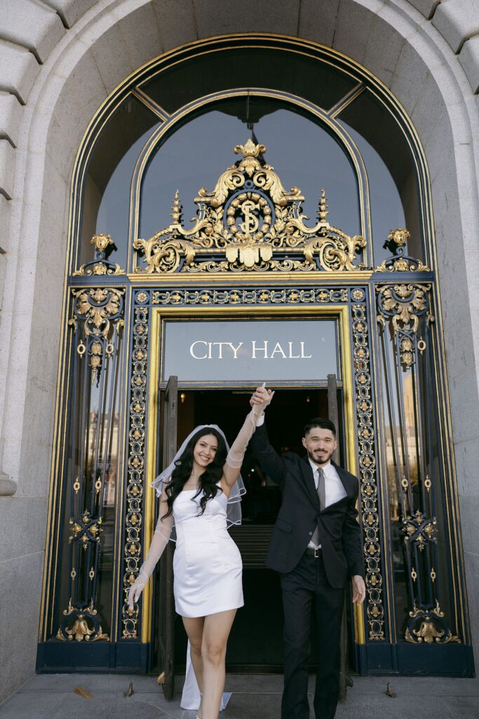 Couple holding hands as they walk out of the City Hall for their San Francisco engagement session