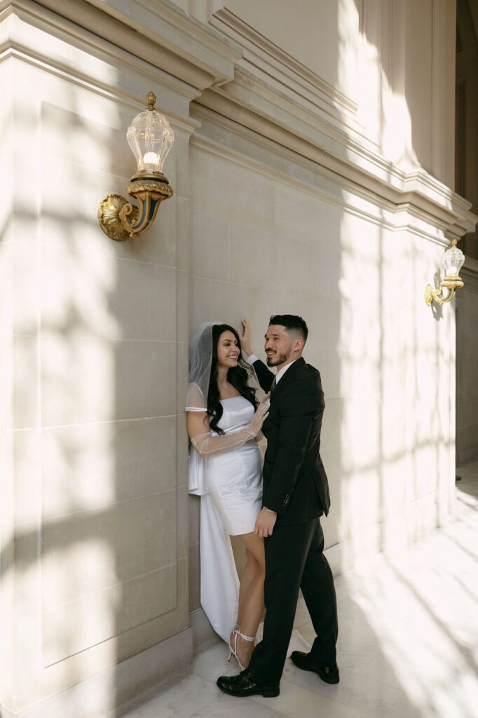 Couple posing against a wall at SF City Hall