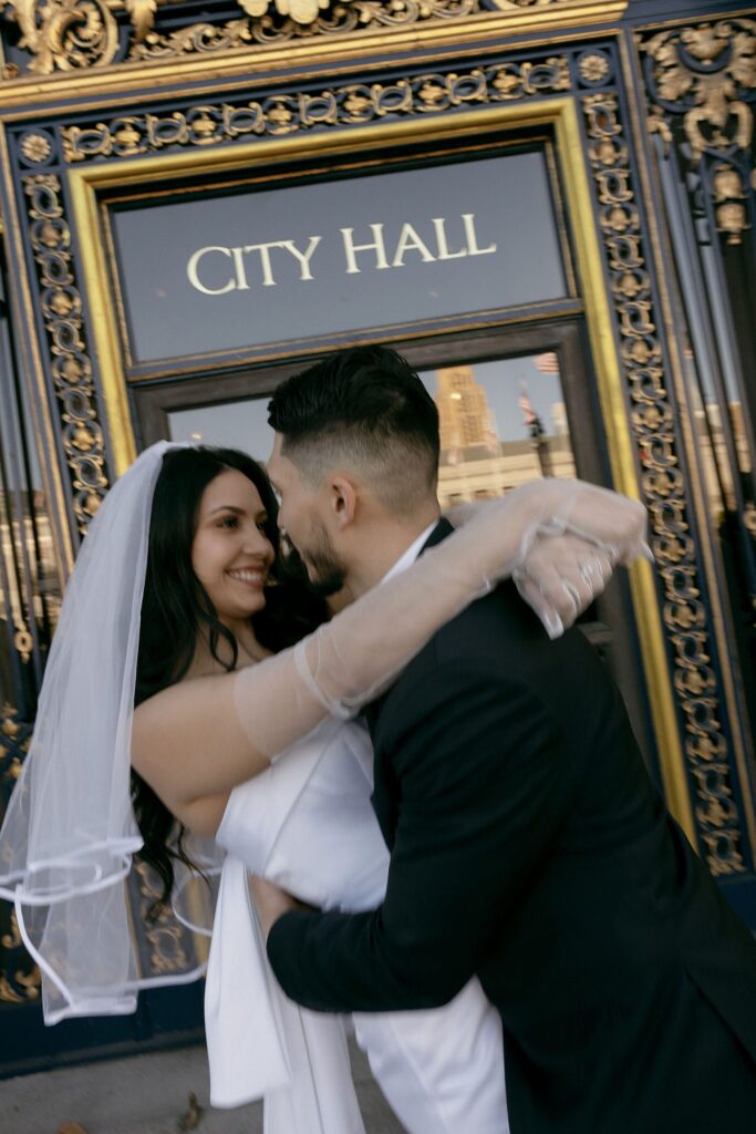 Couple posing outside of San Francisco City Hall for their engagement photos