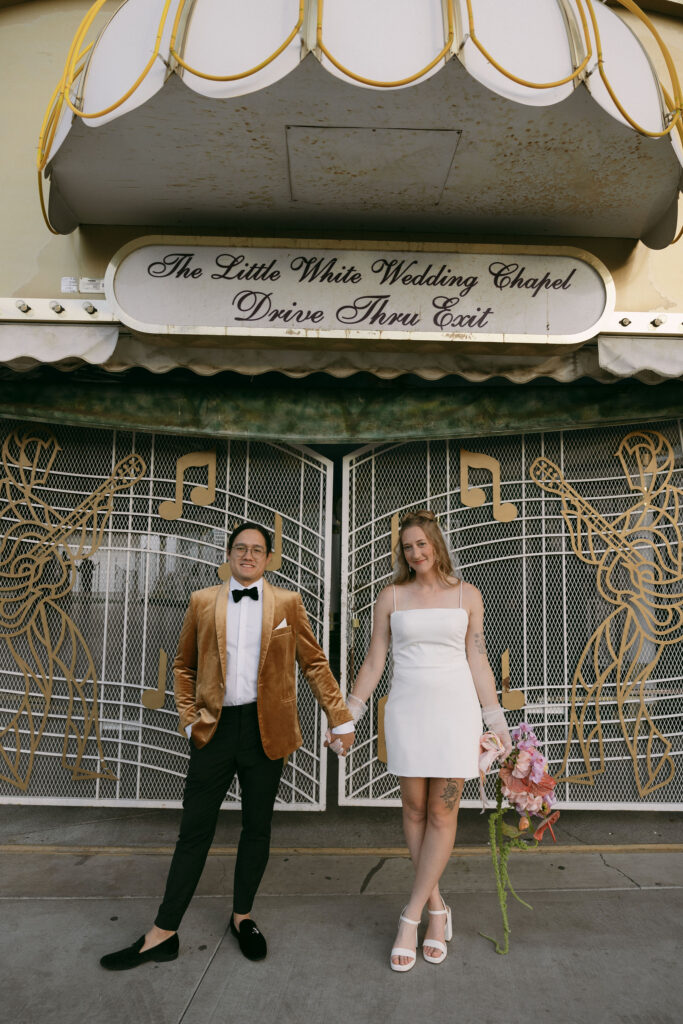 Bride and groom posing outside of Little White Wedding Chapel after their elopement