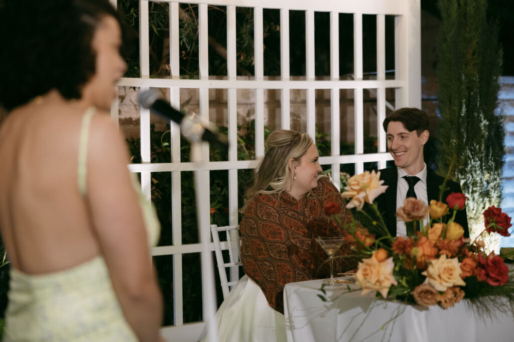 Bride and groom smiling at eachother during speeches