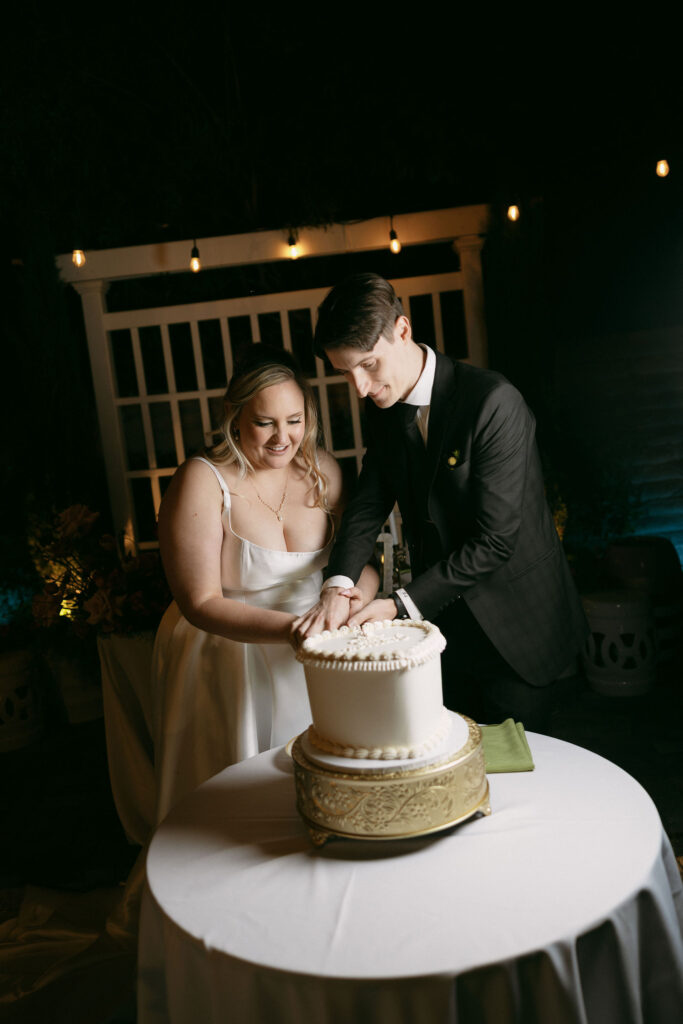 Bride and groom cutting into their wedding cake during their Midcentury Manor wedding reception