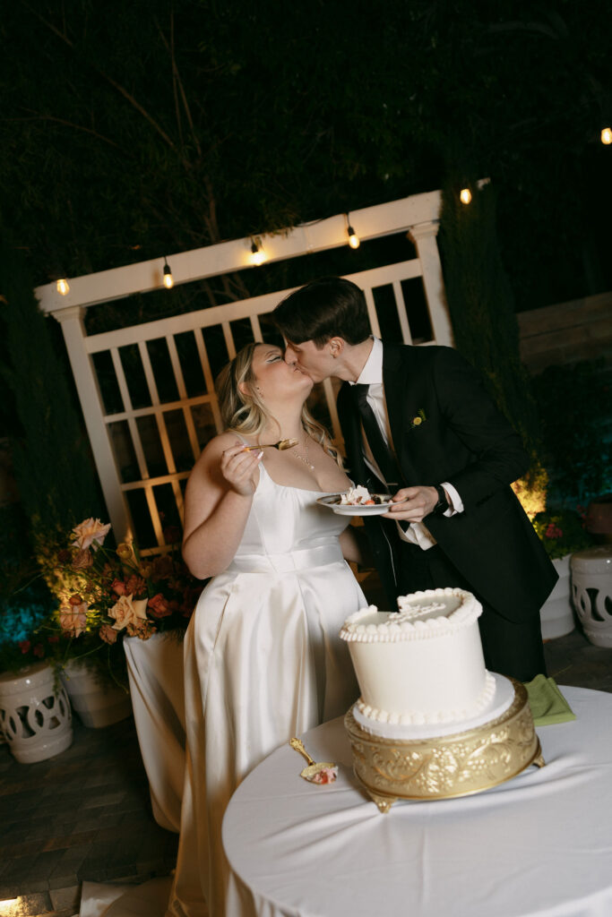 Bride and groom cutting into their wedding cake during their Midcentury Manor wedding reception