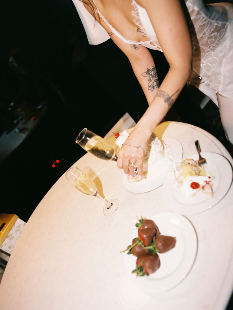 Couple having cake, champagne, and chocolate covered strawberries for their intimate elopement reception at Bellagio Las Vegas