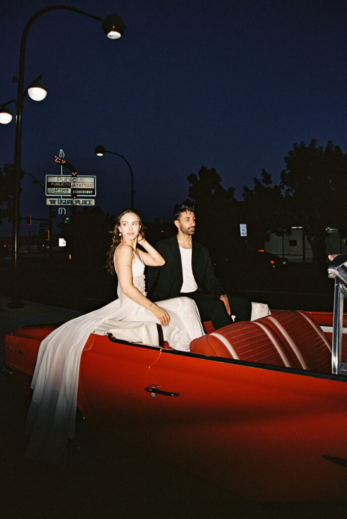 Bride and groom posing inside of their red convertible for their Las Vegas elopement photos