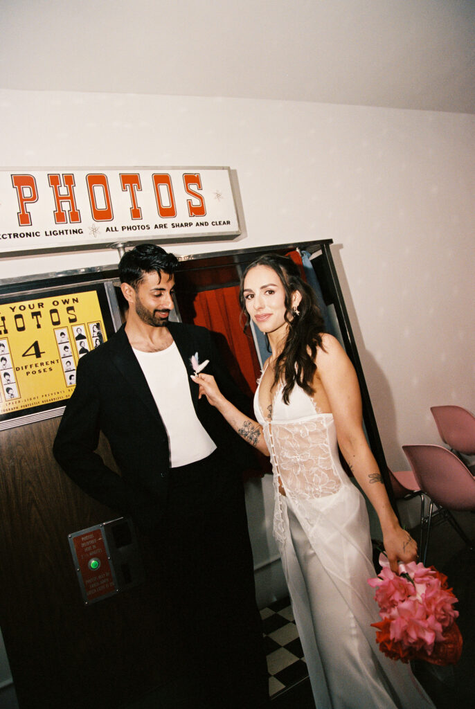 Film Las Vegas elopement shot of a couple posing in front of a photobooth at Sure Thing Chapel