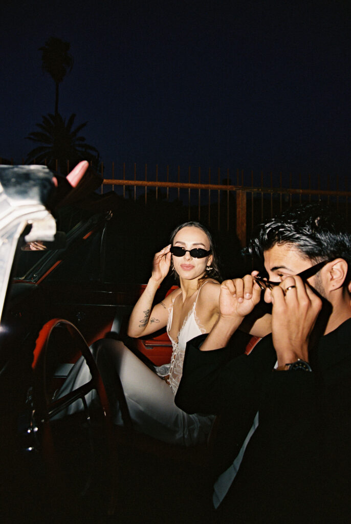 Bride and groom wearing sunglasses for their Las Vegas elopement shoot in a red convertible