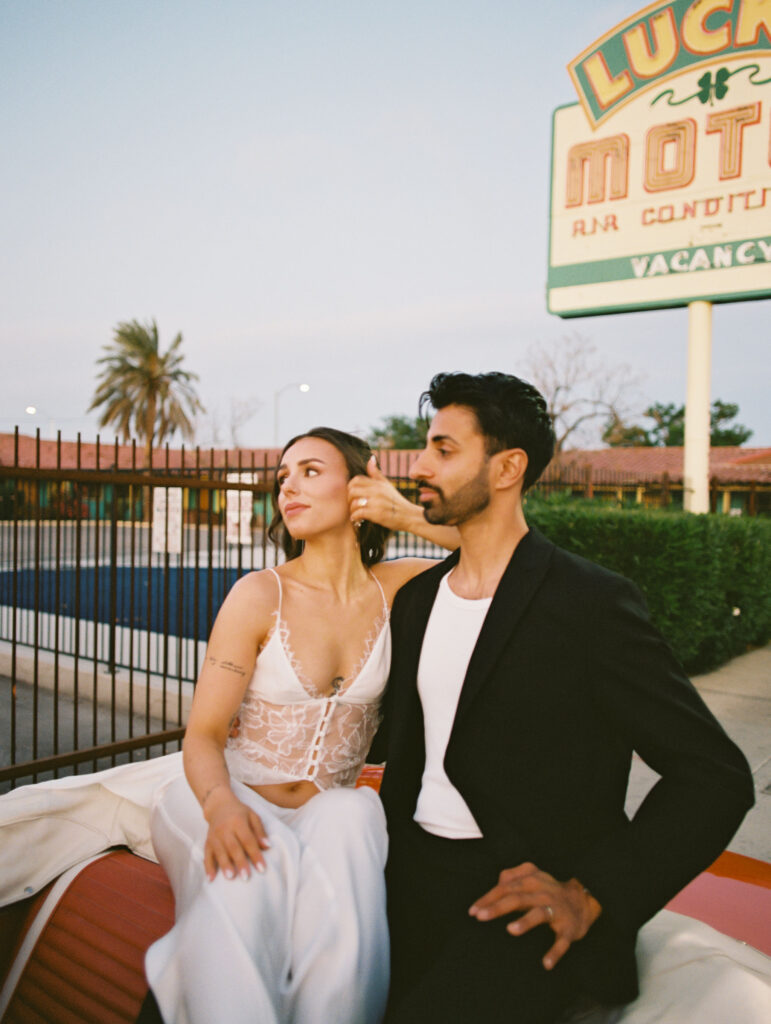 Bride and groom sitting in a red convertible