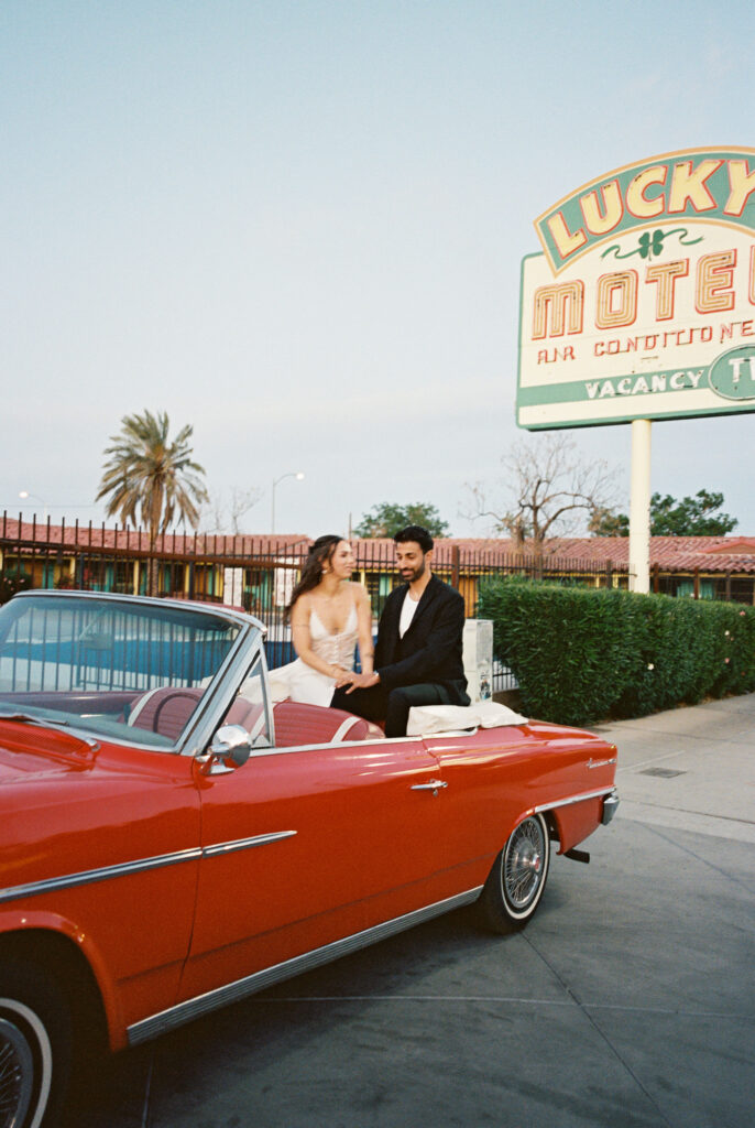 Film photo of a bride and groom sitting in a red convertible for their Las Vegas elopement photos