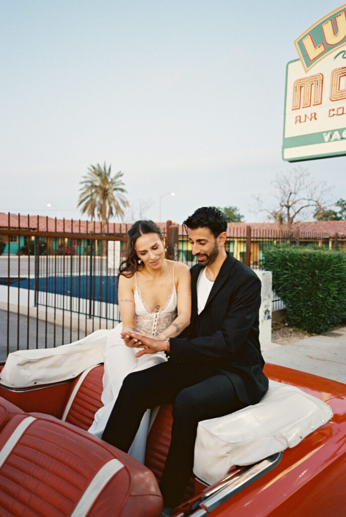Film photo of a bride and groom sitting in a red convertible for their Las Vegas elopement photos