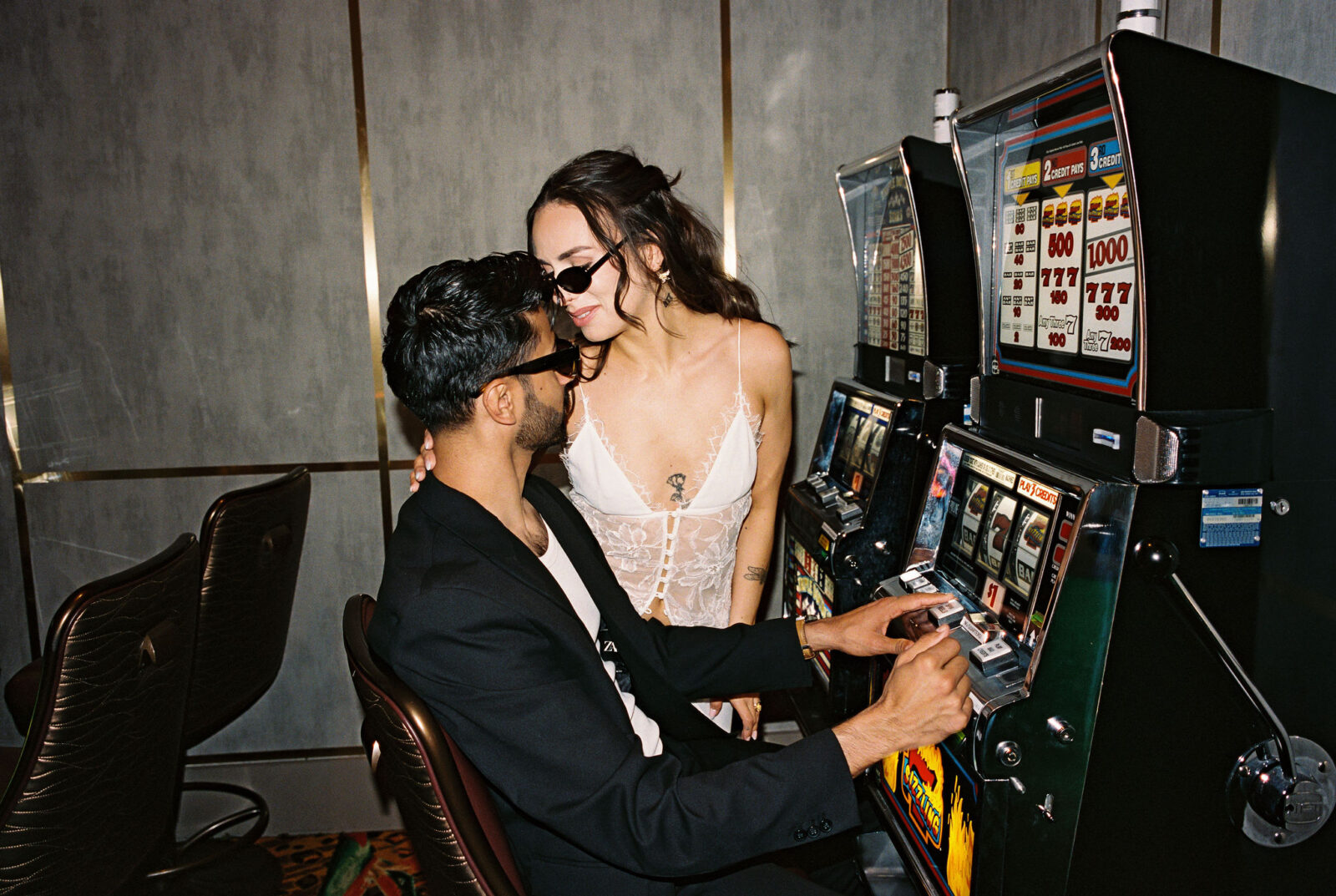 Couple posing in a casino for their film Vegas elopement photos at the slots