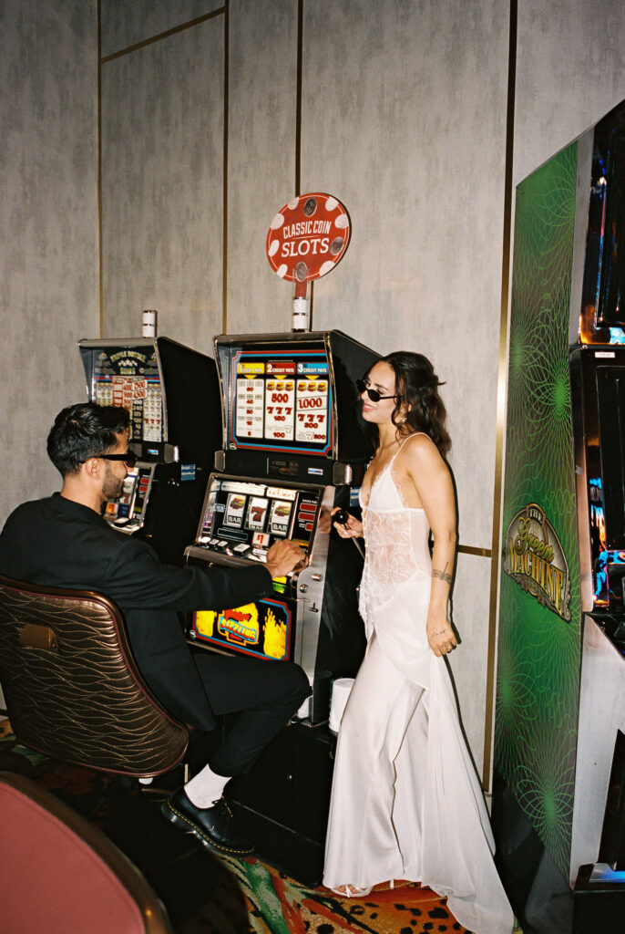 Couple posing in a casino for their film Vegas elopement photos at the slots