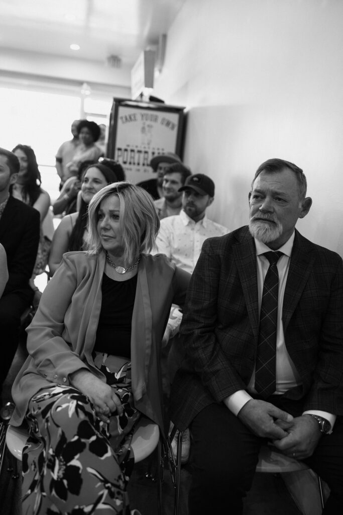 Black and white candid wedding ceremony photo of family getting emotional during the ceremony