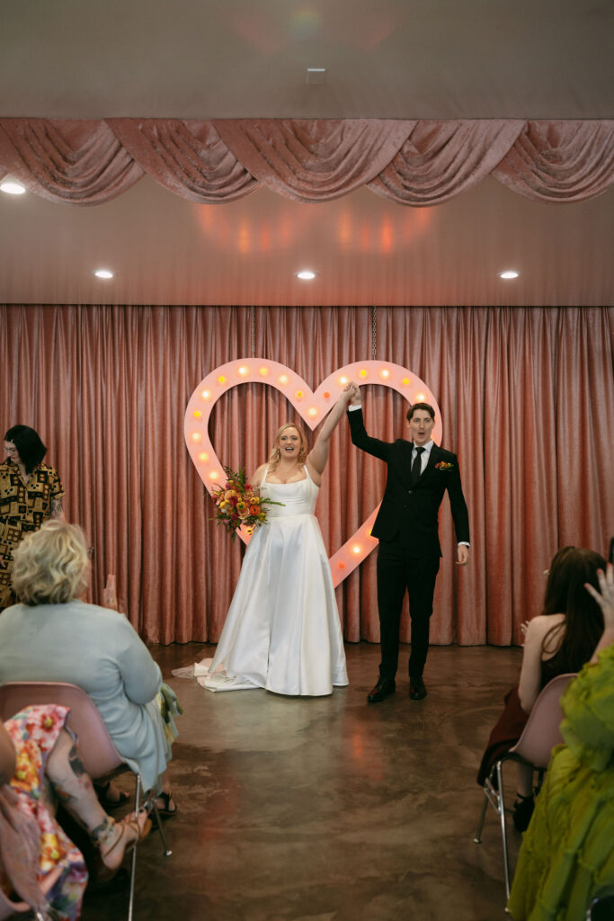 Bride and groom celebrating with their hands in the air after their ceremony