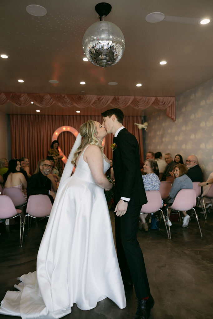 Bride and groom kissing under the disco ball at Sure Thing Chapel