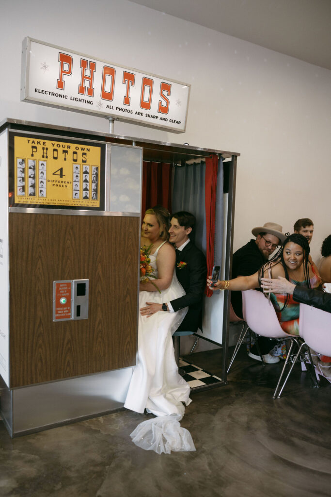 Bride and groom taking photos in the vintage analog photobooth at Sure Thing Chapel