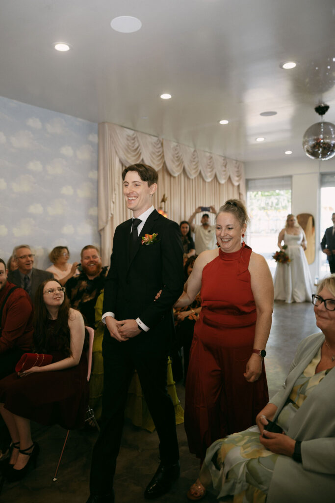 Groom walking down the aisle with his mother