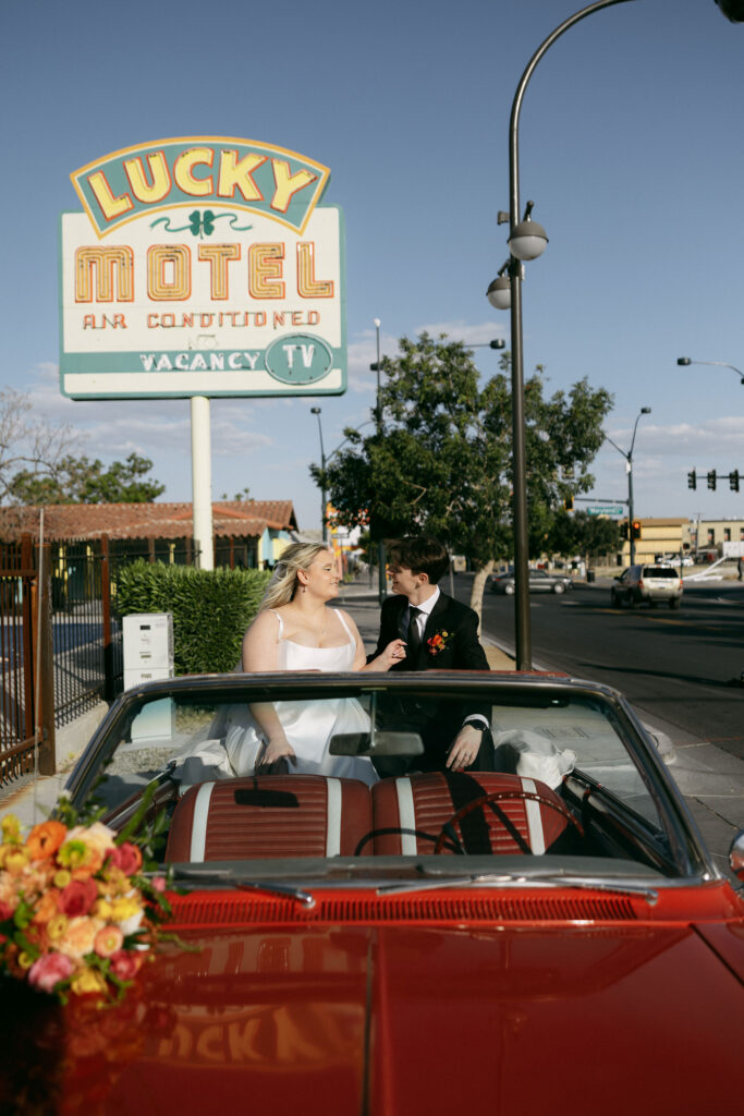 Bride and groom posing with a red convertible after their Las Vegas elopement