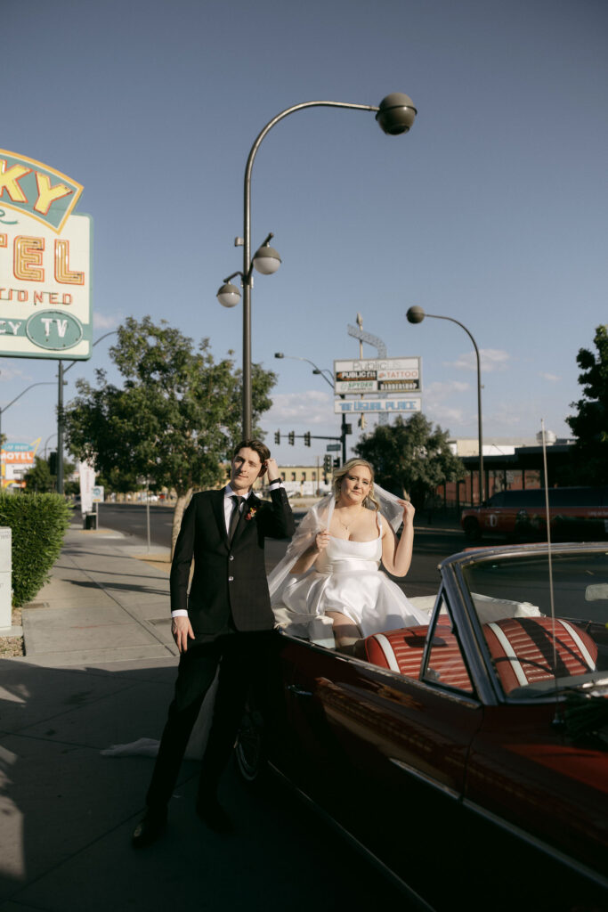 Bride and groom posing with a red convertible after their Las Vegas elopement
