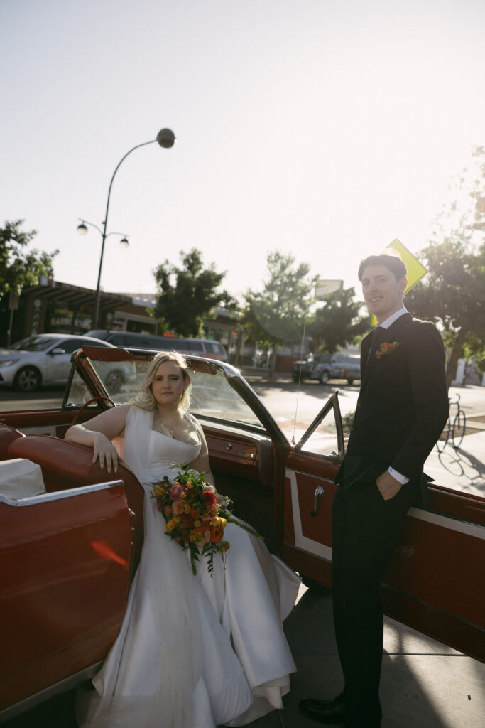 Bride and groom posing with a red convertible after their Las Vegas elopement