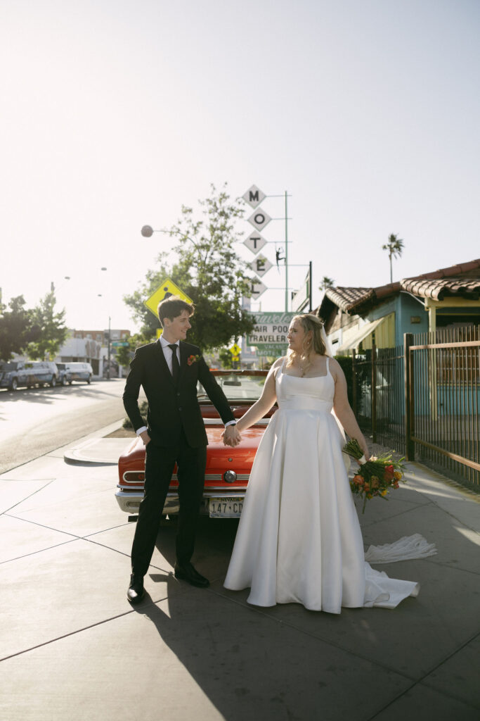 Bride and groom posing with a red convertible after their Las Vegas elopement