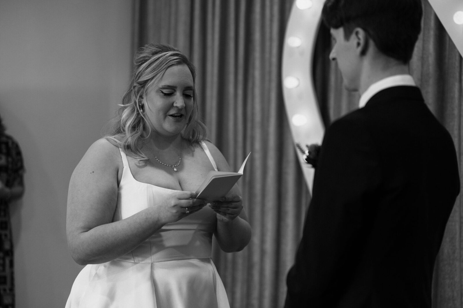 Black and white photo of a bride reading her vows to her groom