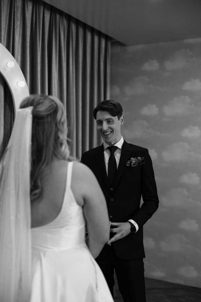 Groom smiling as his bride reads her vows to him